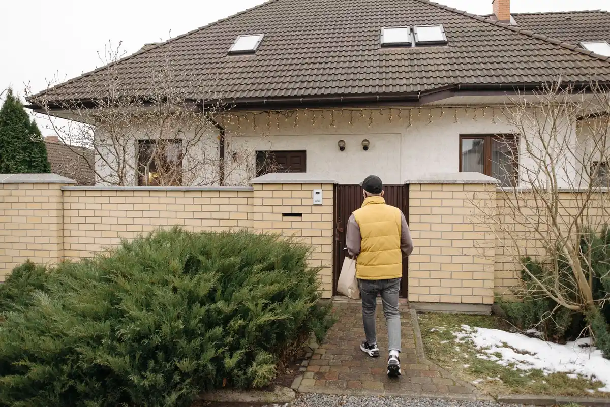 Pest control technician walking up to the front door of a brick house