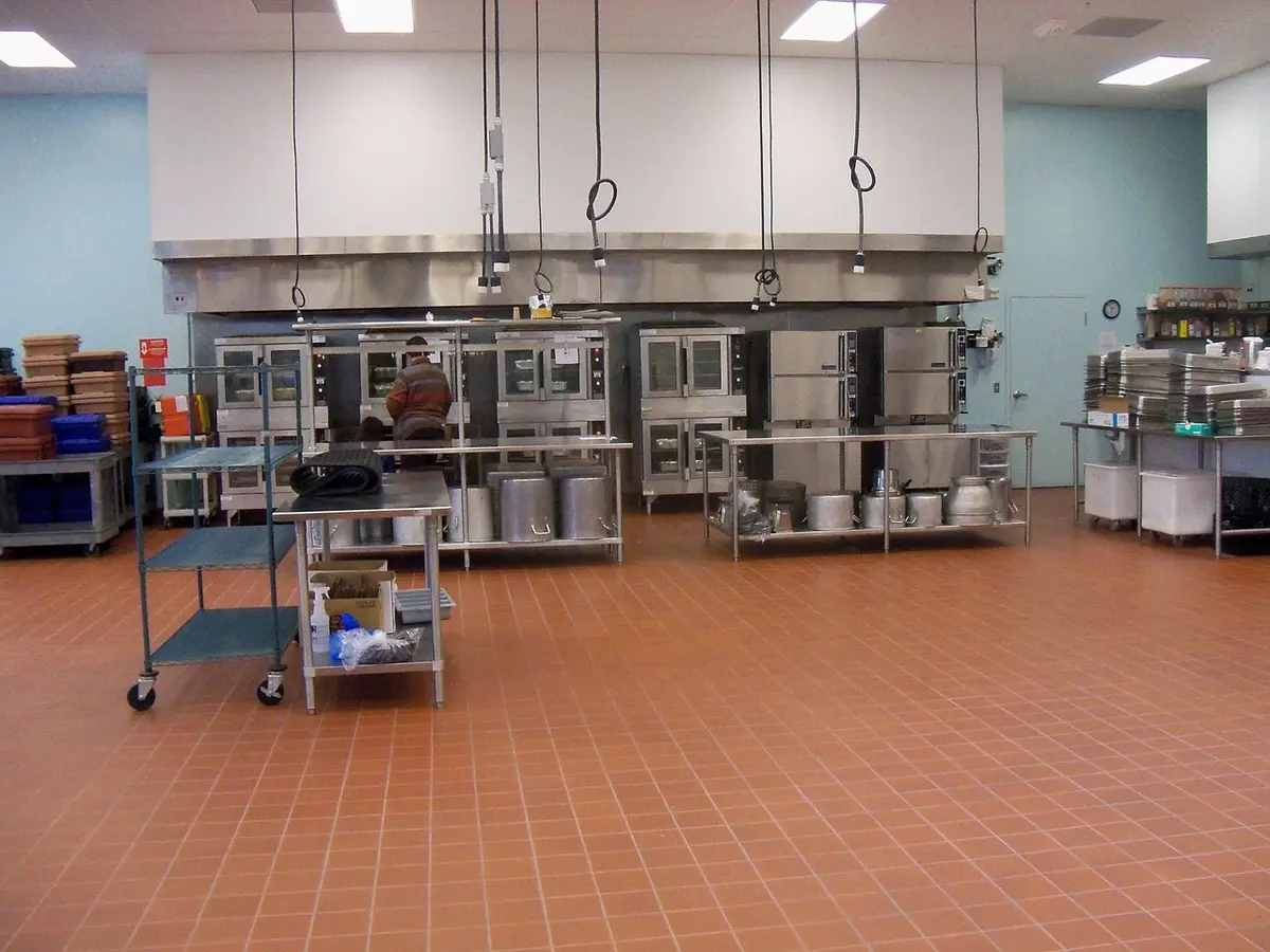 Technician checking a pest monitoring station in a clean commercial kitchen