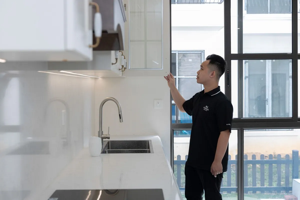 Pest control technician placing a monitor trap behind a refrigerator