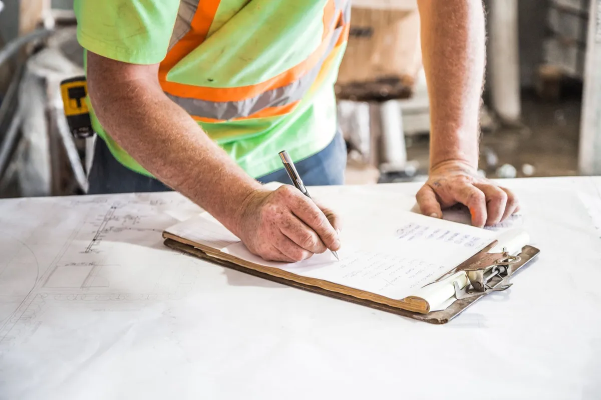 Pest control technician writing a service report on a clipboard