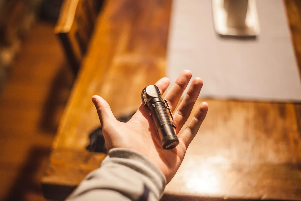 Inspector checking a wood sill plate in an unfinished basement with a flashlight