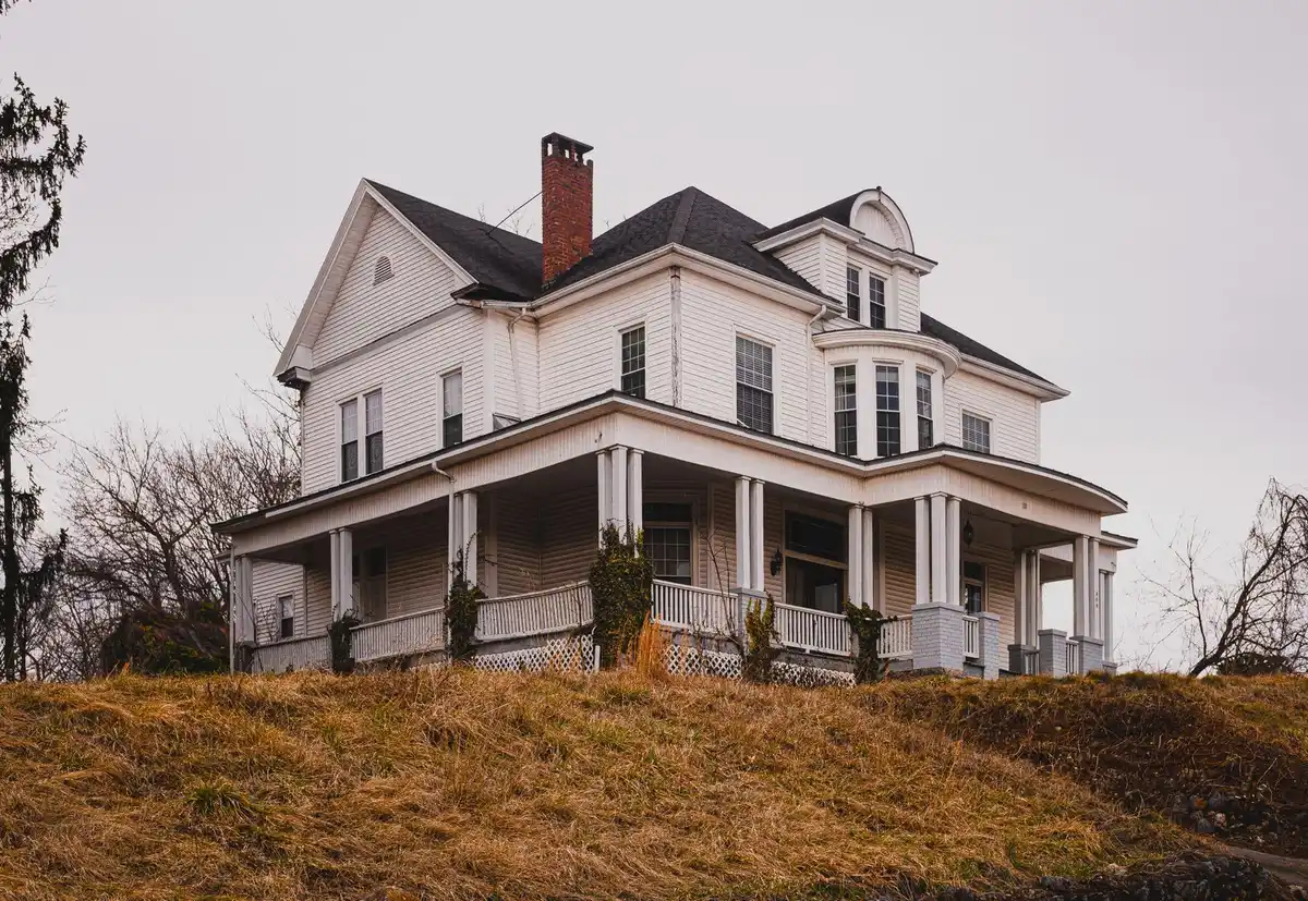 Two-story older home with a front porch on a tree-lined street in autumn