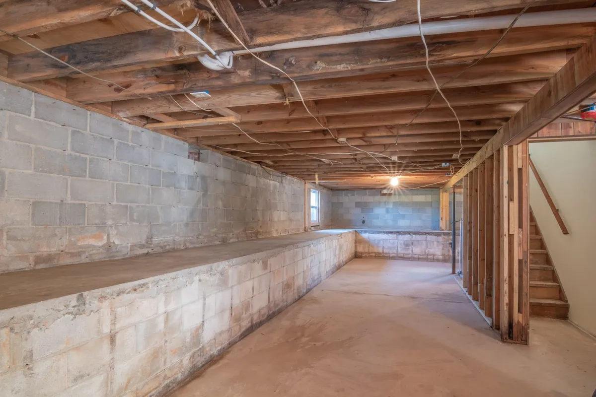 Unfinished basement with a stone and block foundation wall and exposed floor joists