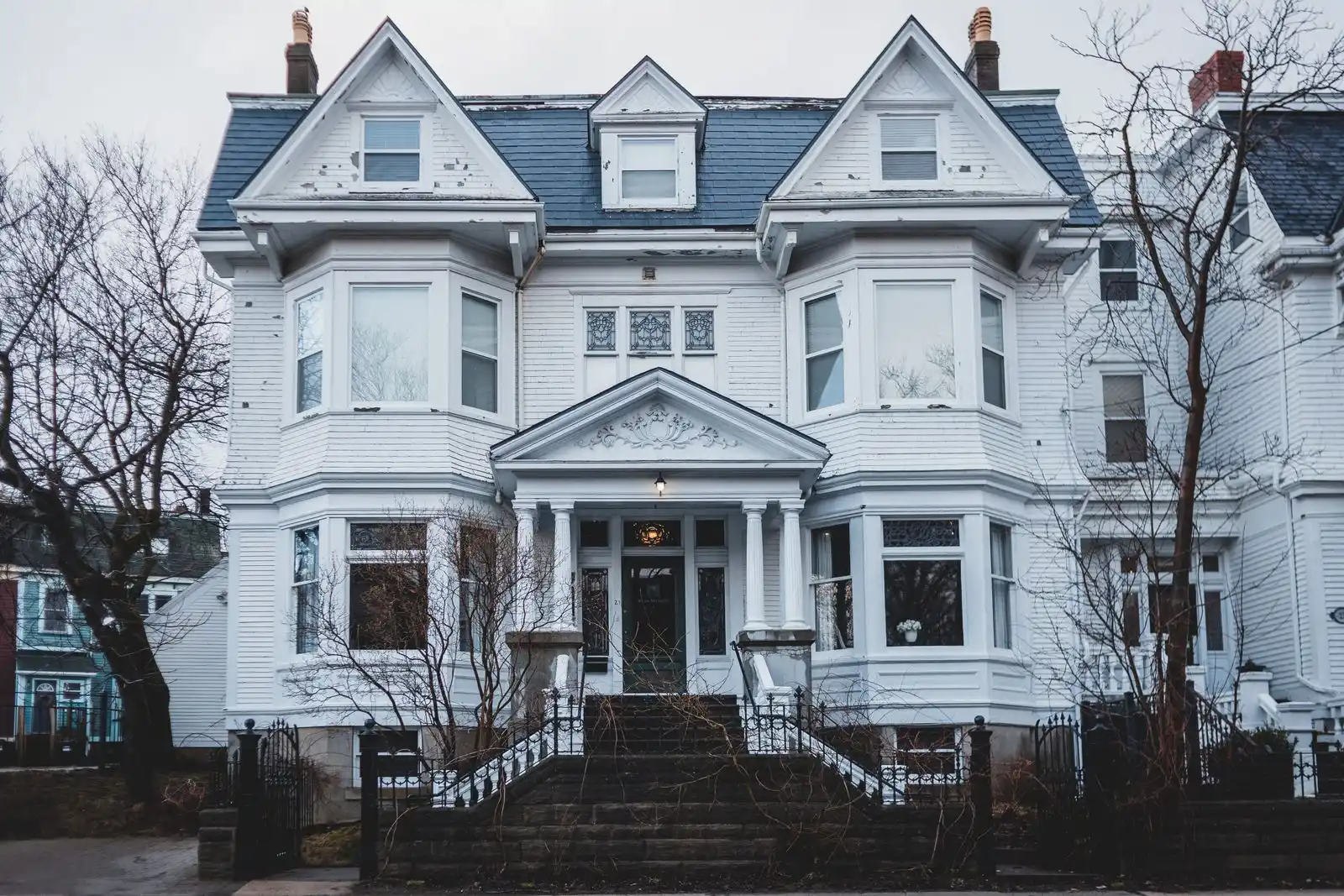Large older two-and-a-half story house with a front porch on a tree-lined street