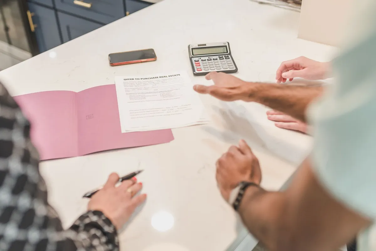 Home buyers reviewing paperwork with a real estate agent at a kitchen table